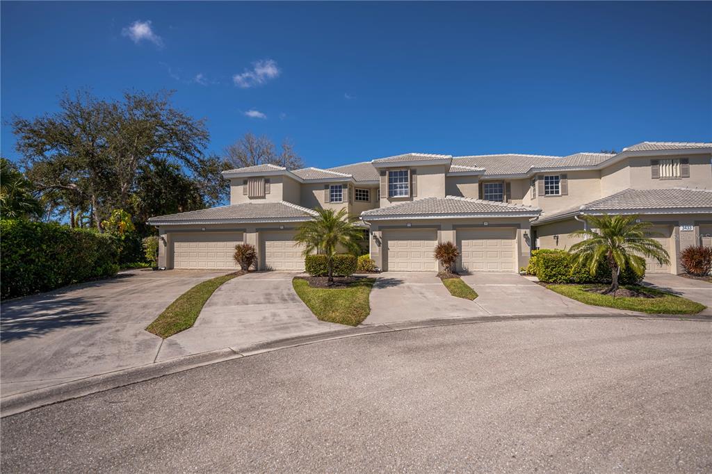 A multi-unit residential building with beige stucco walls, tiled roofs, and attached garages — 3433 GRAND VISTA COURT UNIT 202, PORT CHARLOTTE, FL