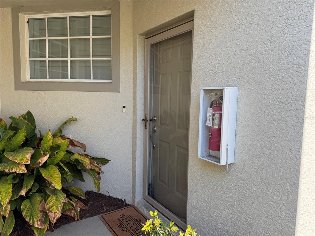 An exterior view of a building entrance with a door, window, and wall-mounted fire extinguisher — 3433 GRAND VISTA COURT UNIT 202, PORT CHARLOTTE, FL