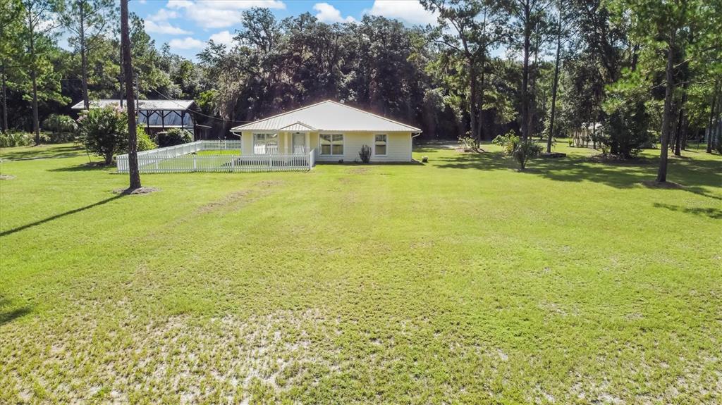 A yellow single-story house sits on a large grassy lot surrounded by mature trees — 17925 SE 49TH PLACE, HAWTHORNE, FL