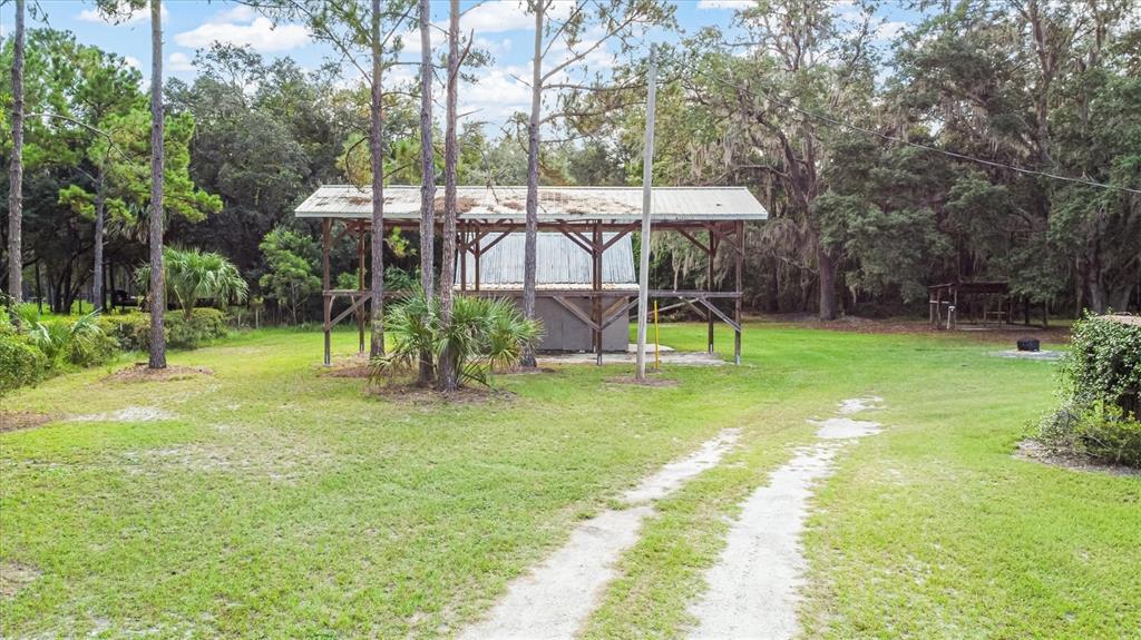 A large wooden pole barn structure stands in a grassy yard with a dirt driveway — 17925 SE 49TH PLACE, HAWTHORNE, FL