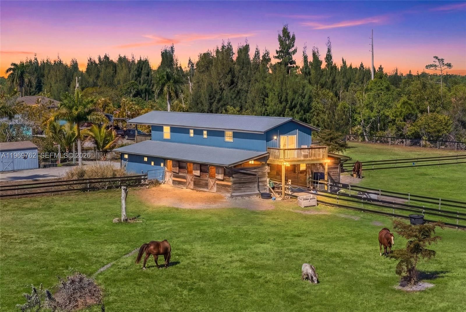 A blue two-story barn with horse stalls and a wooden balcony sits in a grassy pasture — 6050 Stringfellow Rd, Saint James City FL 33956, SAINT JAMES CITY, FL