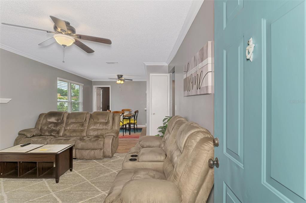A living room with two brown reclining sofas, a coffee table, and a dining area — 3802 59TH AVENUE W UNIT 4113, BRADENTON, FL