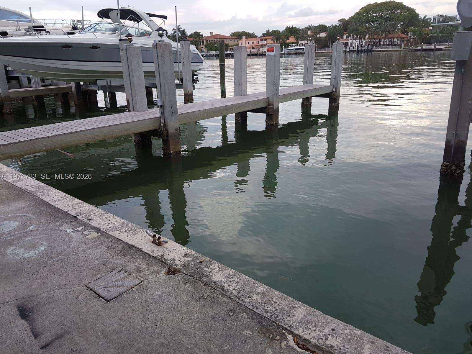 A concrete dock extends into a canal with a boat moored nearby — 5401 Collins Ave #13-17, Miami Beach FL 33140, MIAMI BEACH, FL