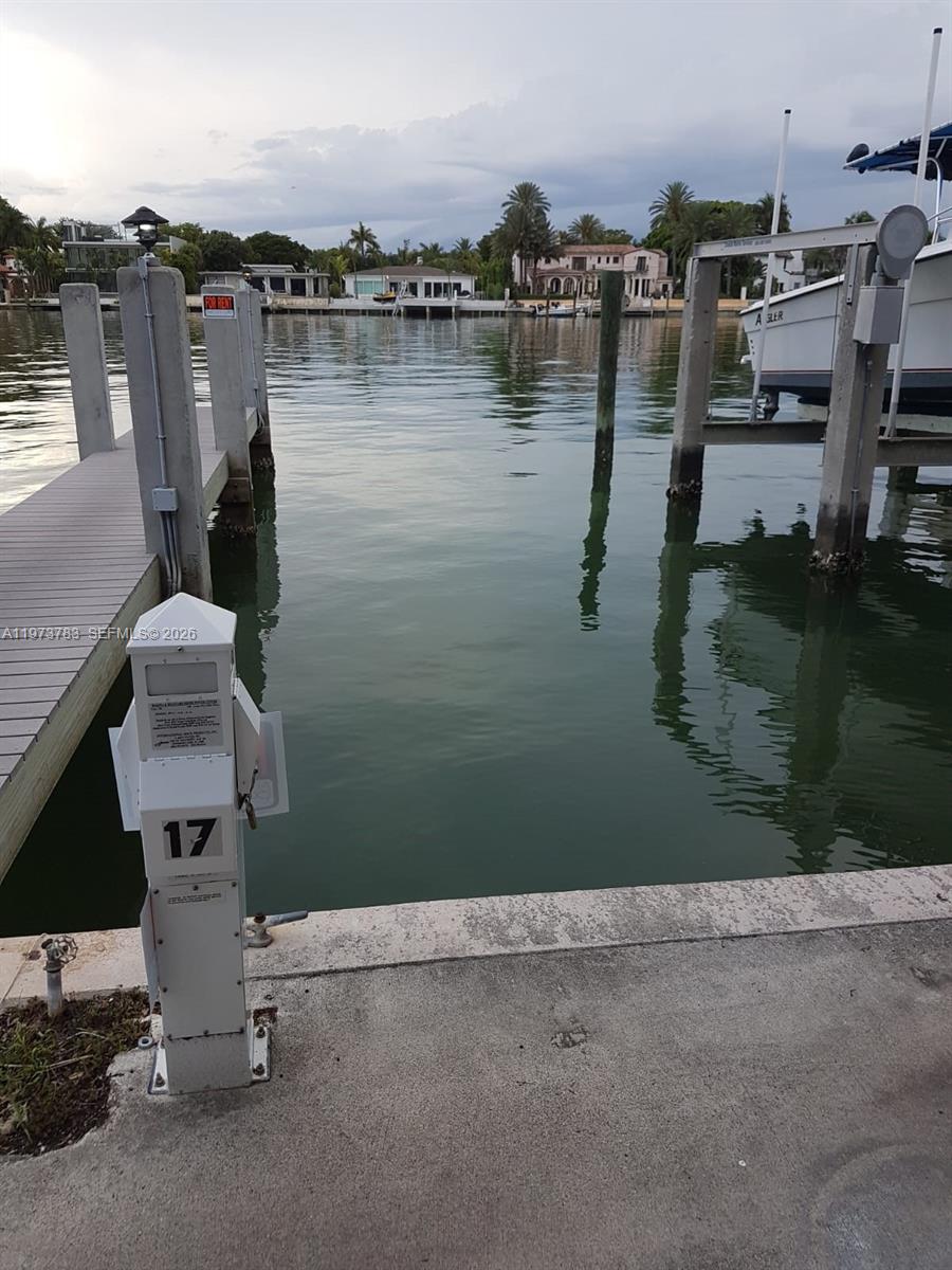 A boat slip with a wooden dock and a utility pedestal overlooks a calm canal — 5401 Collins Ave #13-17, Miami Beach FL 33140, MIAMI BEACH, FL