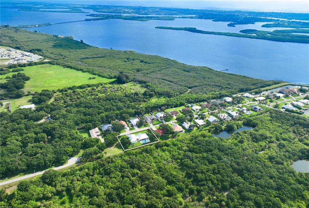 An aerial view shows a house with a pool surrounded by dense forest and water — 4255 79TH STREET, VERO BEACH, FL