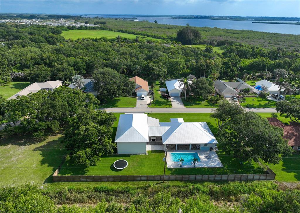 An aerial view of a house with a white metal roof, pool, and fenced backyard — 4255 79TH STREET, VERO BEACH, FL