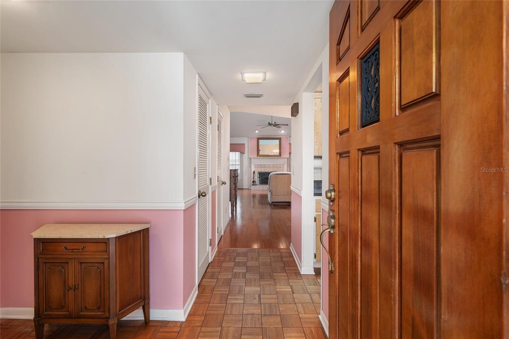 An entryway features a wooden door, pink wainscoting, and parquet flooring leading to a living room — 2064 SE 37TH COURT CIRCLE, OCALA, FL