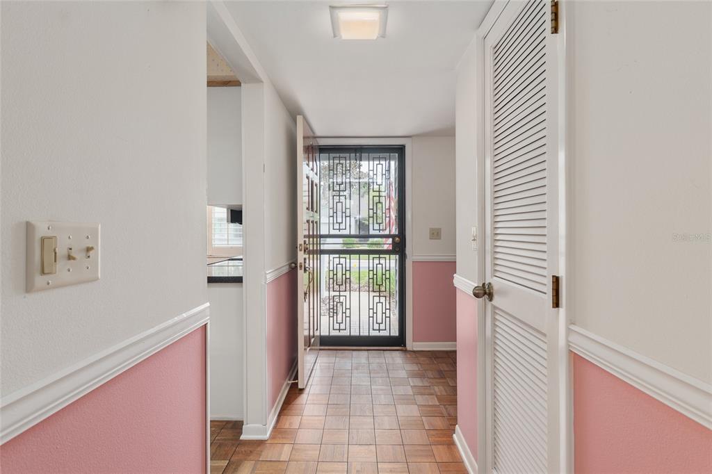 An entryway features pink wainscoting, tiled flooring, a louvered closet door, and a screen door — 2064 SE 37TH COURT CIRCLE, OCALA, FL