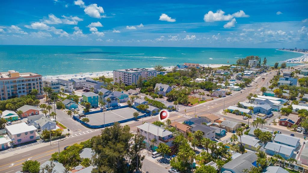 An aerial view shows a multi-story building near a beach with surrounding houses and roads — 12201 GULF BOULEVARD, TREASURE ISLAND, FL