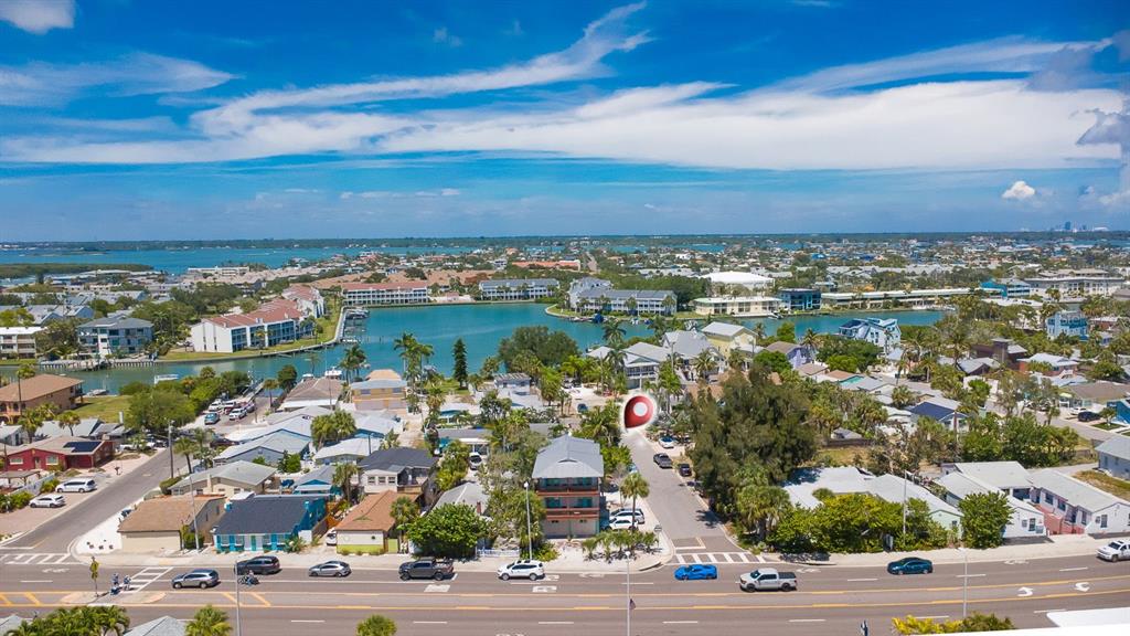 An aerial view shows a coastal neighborhood with houses, a bay, and a main road — 12201 GULF BOULEVARD, TREASURE ISLAND, FL