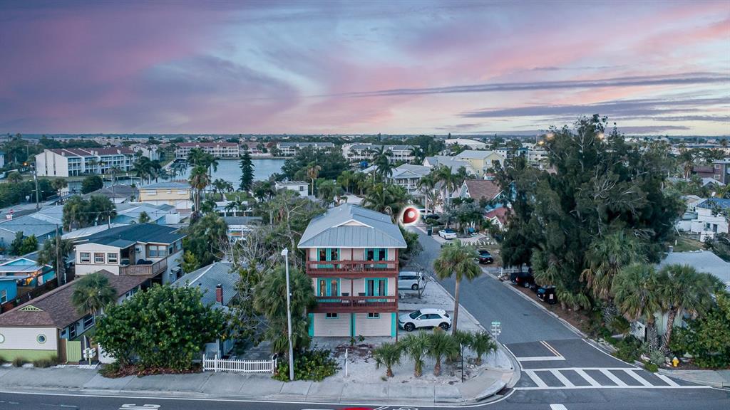 An aerial view shows a three-story house with balconies located on a corner lot — 12201 GULF BOULEVARD, TREASURE ISLAND, FL