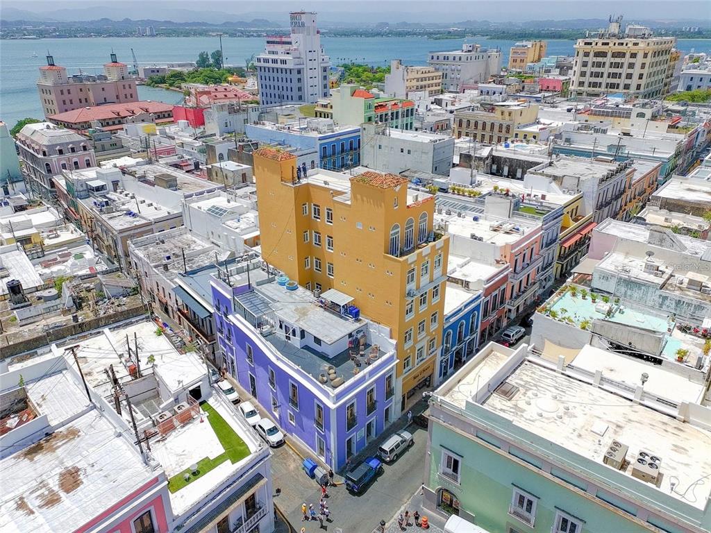 An aerial view of a colorful urban streetscape featuring a prominent yellow high-rise building — 266 SAN FRANCISCO UNIT 266, SAN JUAN, PR