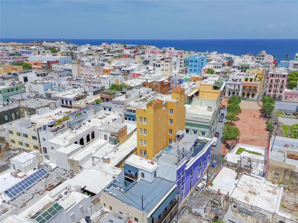 An aerial view shows a dense urban neighborhood with colorful buildings and the ocean beyond — 266 SAN FRANCISCO UNIT 266, SAN JUAN, PR