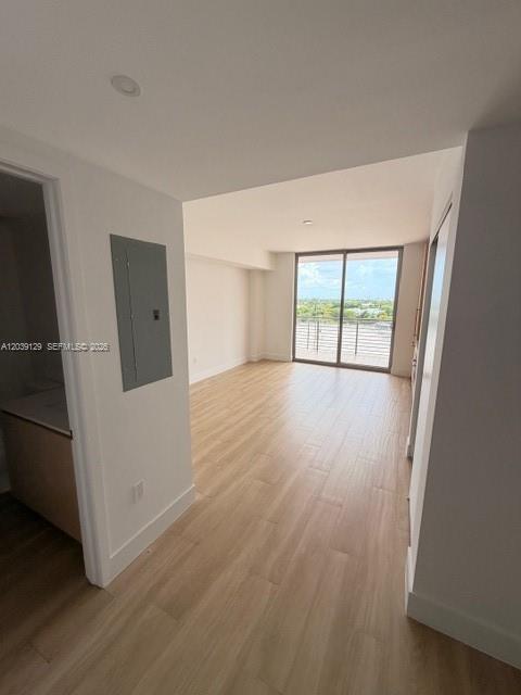 An interior view of an empty room with light wood flooring and a balcony door — 90 NE 32nd St # 823, Miami FL 33137, MIAMI, FL