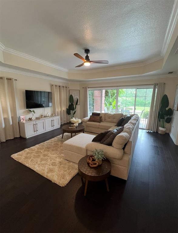 A living room features a sectional sofa, a television console, and dark hardwood flooring — 7612 CABANA COURT UNIT 101, REUNION, FL