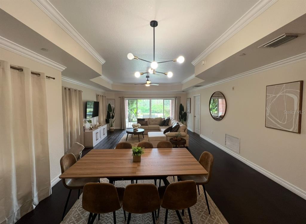 A dining area with a wooden table leads into a living room with a sectional sofa — 7612 CABANA COURT UNIT 101, REUNION, FL