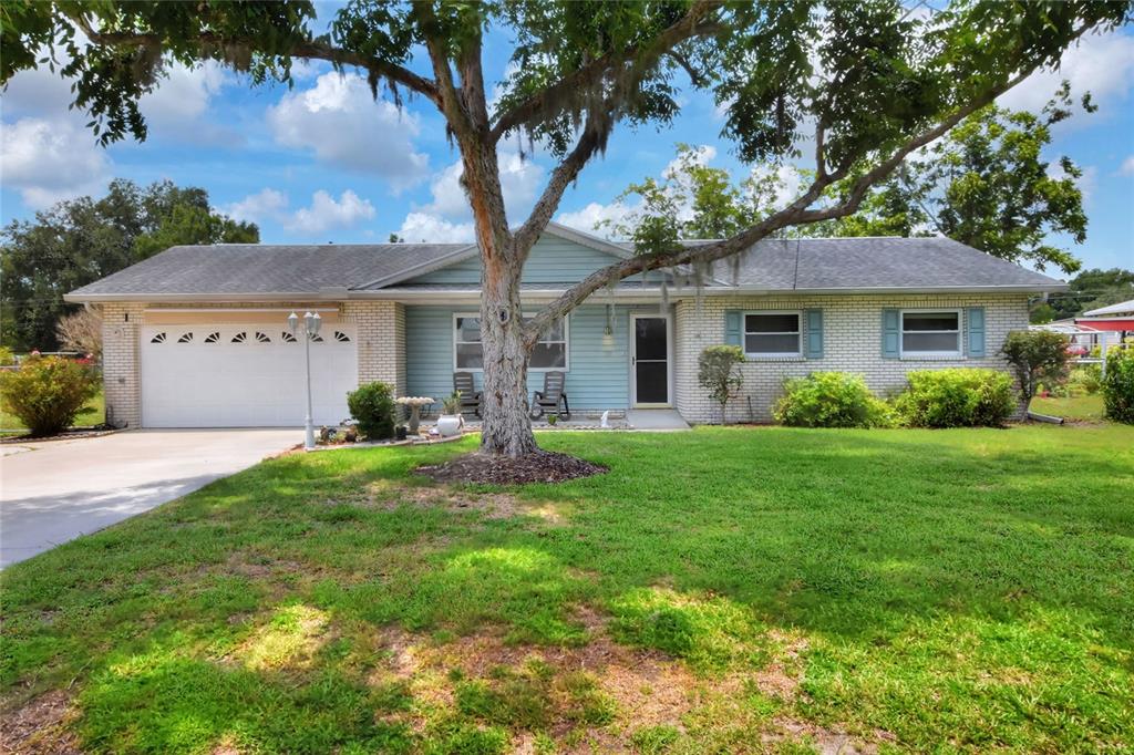 A single-story house with a white brick exterior, light blue siding, and a large tree — 6739 FARRIS DRIVE, LAKELAND, FL