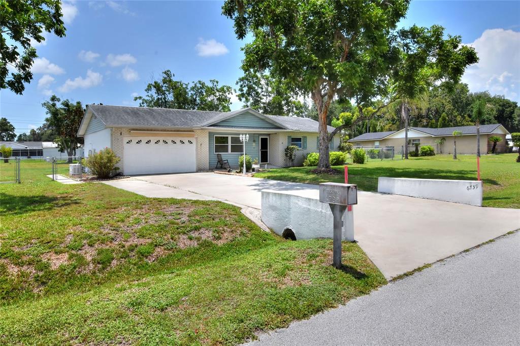 A single-story house with a white garage and a concrete driveway leading to the street — 6739 FARRIS DRIVE, LAKELAND, FL