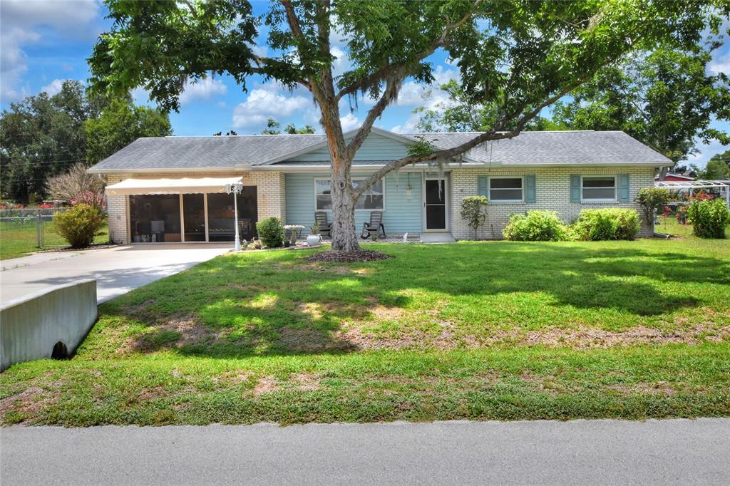 A single-story house with a light blue facade, brick accents, and a large front tree — 6739 FARRIS DRIVE, LAKELAND, FL