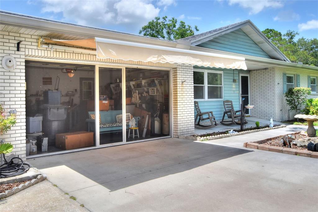A house exterior features a garage with a screen door, an awning, and a porch — 6739 FARRIS DRIVE, LAKELAND, FL