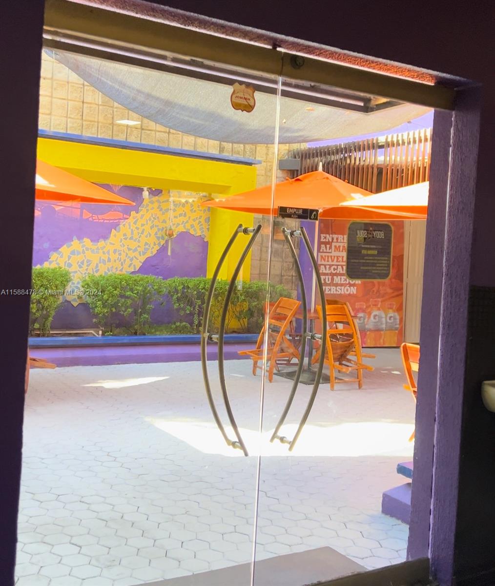 A view through a glass door shows an outdoor patio with orange umbrellas and chairs — Carrera 64 85-53, 00000, FL