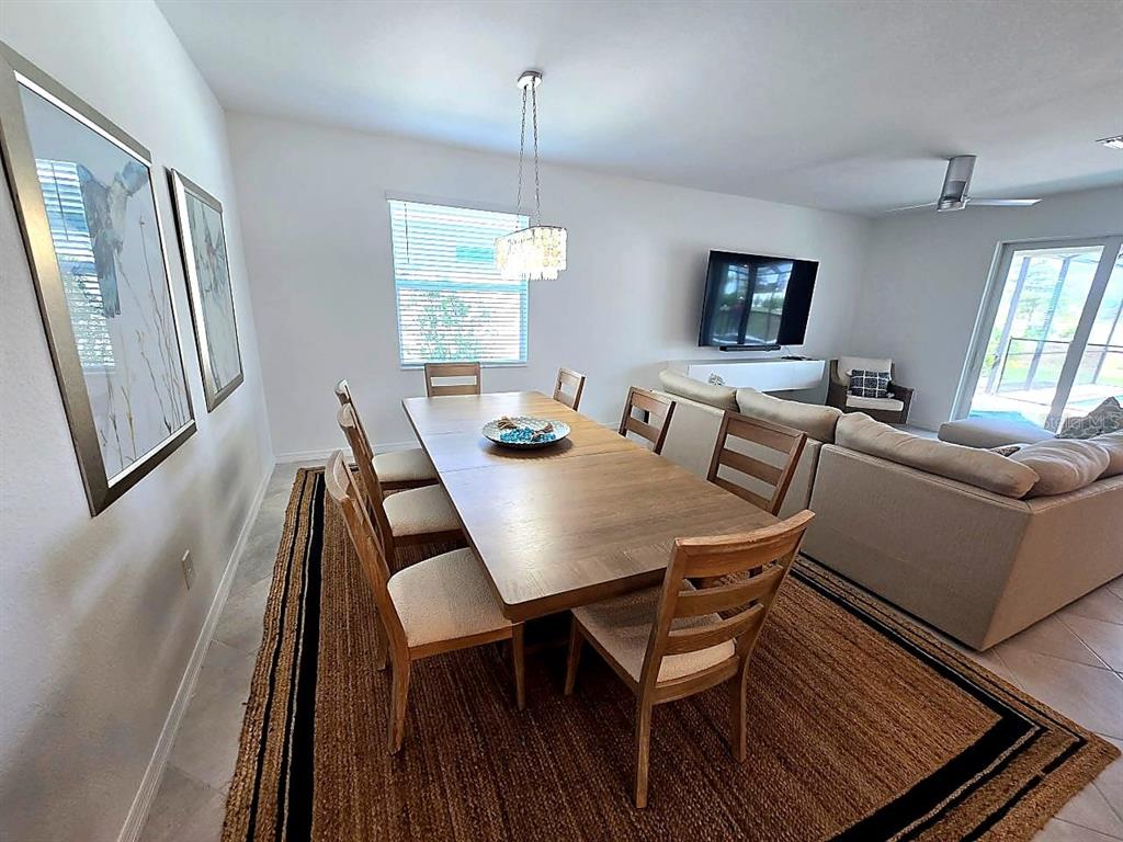 A dining area with a wooden table and chairs sits on a large textured rug — 11399 PINOT DRIVE, VENICE, FL