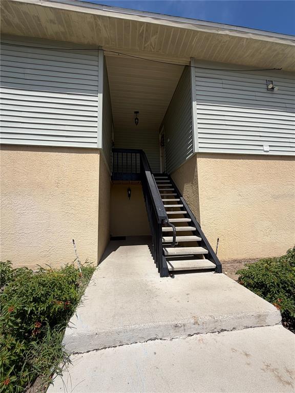 An exterior view shows a concrete walkway leading to a staircase and a recessed entryway — 502 GOLDEN RAINTREE PLACE, BRANDON, FL