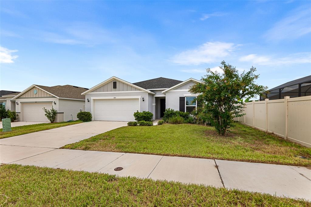 An open-concept kitchen and living area with white cabinets, granite countertops, and tile flooring — 1425 ENGELBERG STREET, WINTER HAVEN, FL