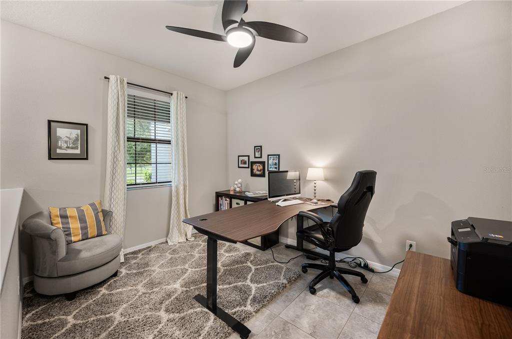 A home office features a desk, gaming chair, armchair, and a ceiling fan — 17616 TERRAZZO WAY, LAND O LAKES, FL