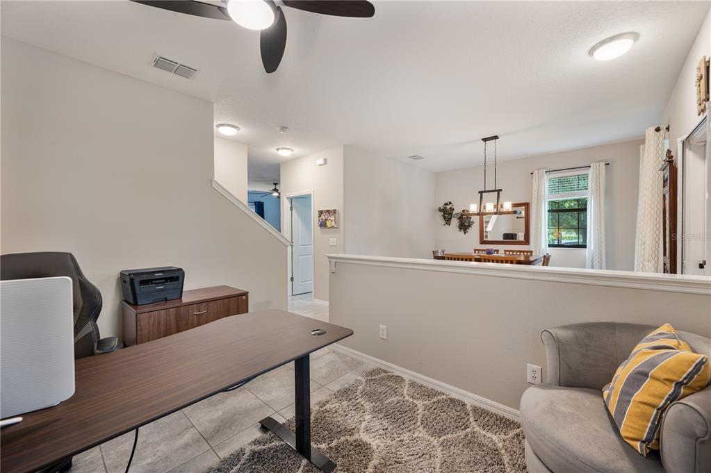 A home office area with a desk and chair overlooks a dining room — 17616 TERRAZZO WAY, LAND O LAKES, FL