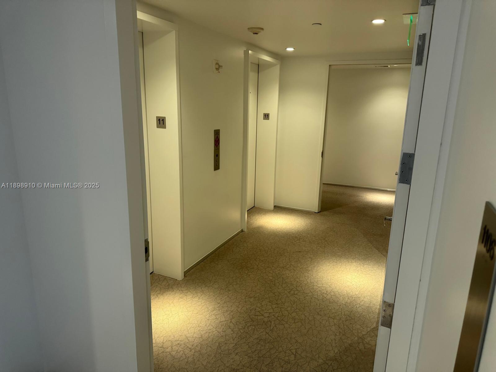 A hallway with carpeted flooring leads to two elevator doors marked with the number eleven — 1040 Biscayne Blvd # 1106, Miami FL 33132, MIAMI, FL