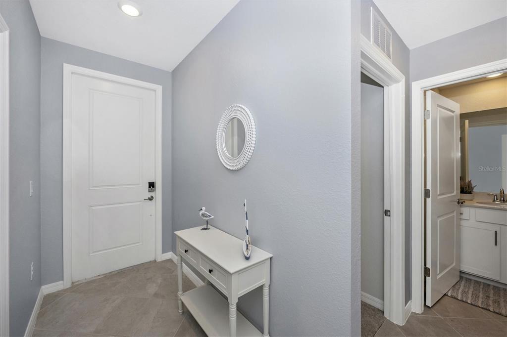 A foyer with light gray walls, tile flooring, a white console table, and a bathroom entrance — 12240 WELLEN GOLF STREET UNIT 207, VENICE, FL