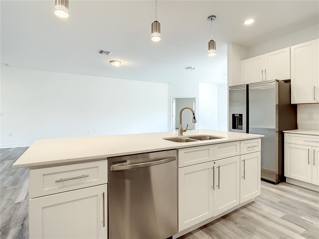 A kitchen island with a stainless steel dishwasher and sink sits before white cabinets — 14210 LUXO AVENUE, PORT CHARLOTTE, FL