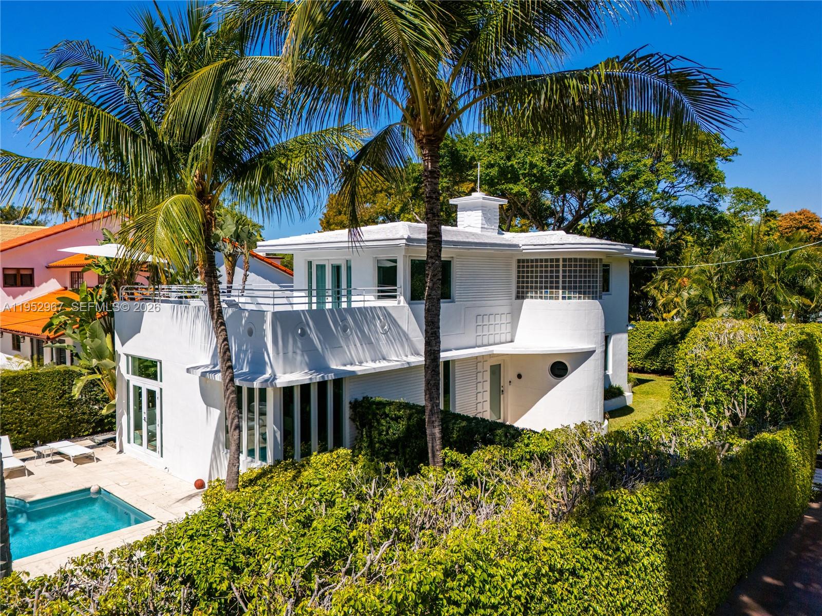 A white two-story Art Deco house features a swimming pool and lush surrounding landscaping — 4580 Post Ave, Miami Beach FL 33140, MIAMI BEACH, FL
