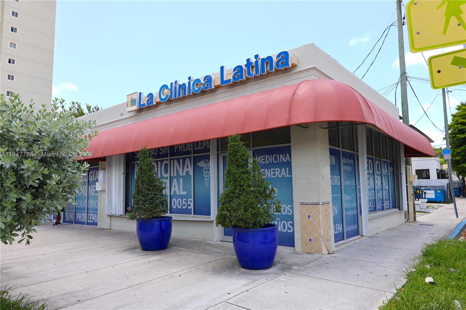 The exterior of a medical clinic building features a red awning and blue signage — 1058 SW 1st St, Miami FL 33130, MIAMI, FL