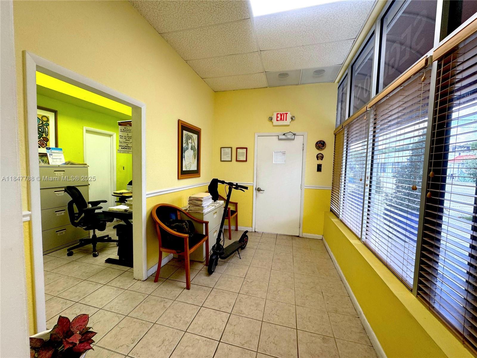 An office waiting area features yellow walls, tile flooring, a scooter, and large windows — 1058 SW 1st St, Miami FL 33130, MIAMI, FL