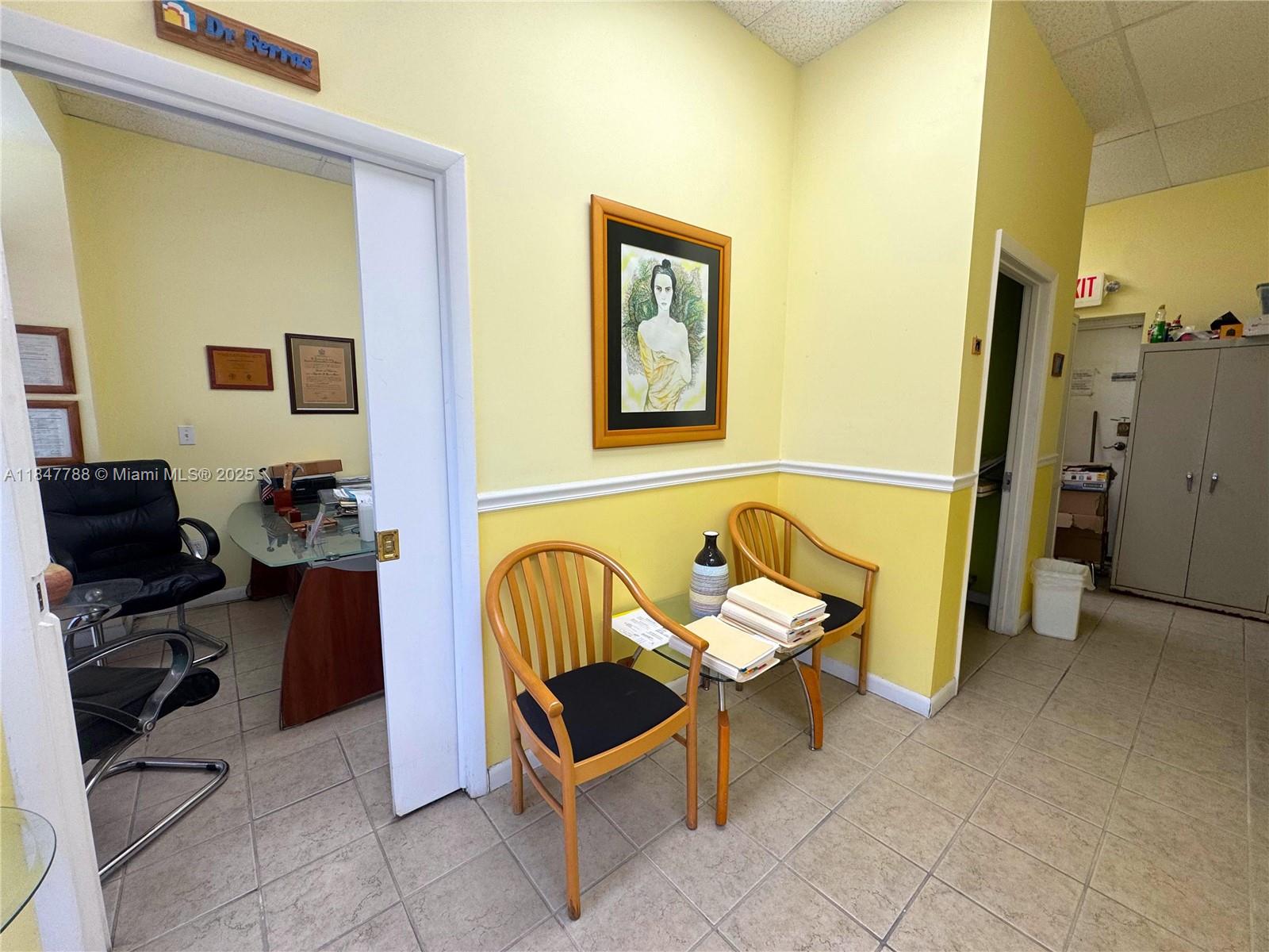 A waiting area with two wooden chairs and a small table leads into an office — 1058 SW 1st St, Miami FL 33130, MIAMI, FL