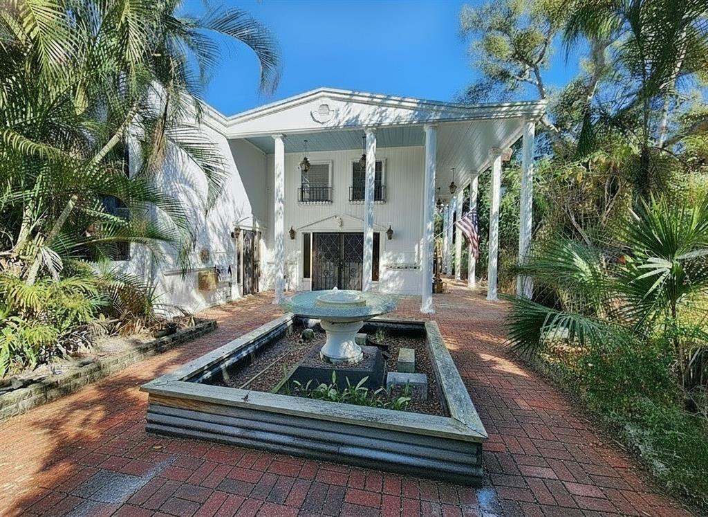 A white two-story house with a columned porch and a central fountain in the foreground — 286 SHAMROCK DRIVE, VENICE, FL
