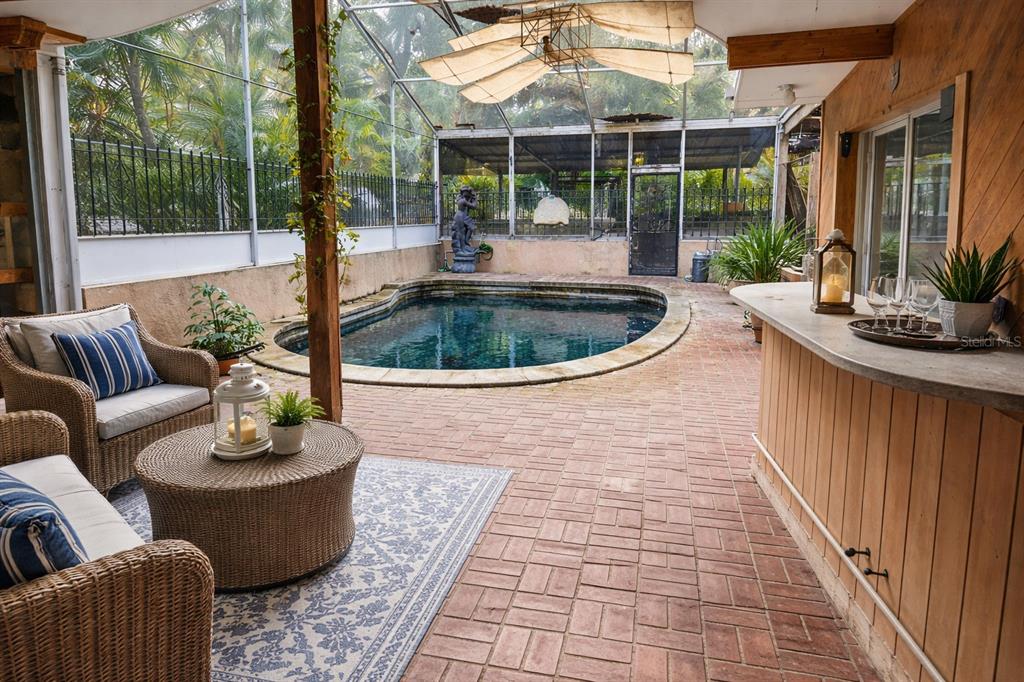 A screened-in patio features a brick floor, a small pool, and a wooden bar — 286 SHAMROCK DRIVE, VENICE, FL