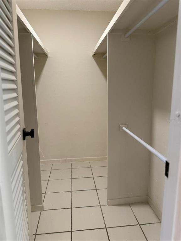 A walk-in closet with white walls, white tile flooring, and built-in shelving with hanging rods — 702 PISOS DE MIRAMAR, SAN JUAN, PR