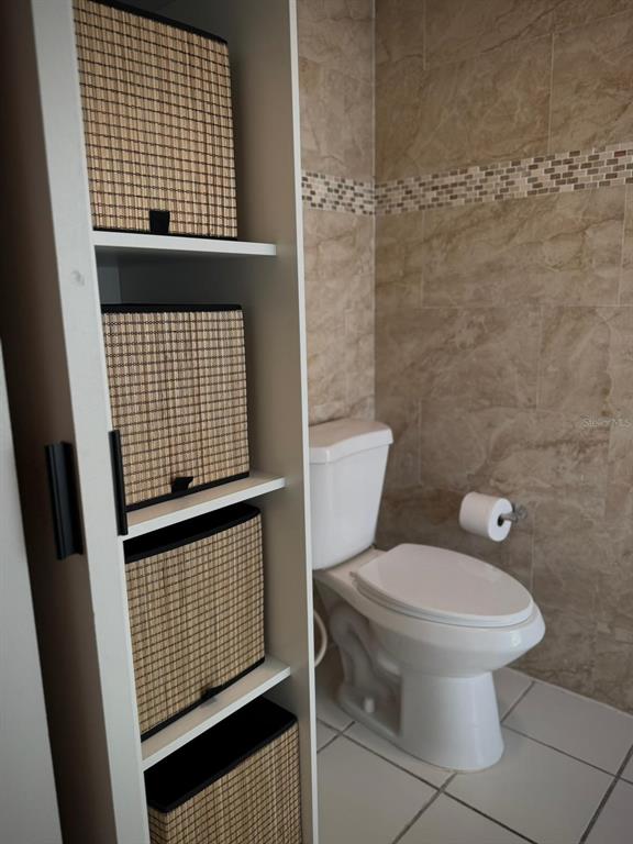 A bathroom features a white toilet, tiled walls, and a tall shelving unit with woven baskets — 702 PISOS DE MIRAMAR, SAN JUAN, PR