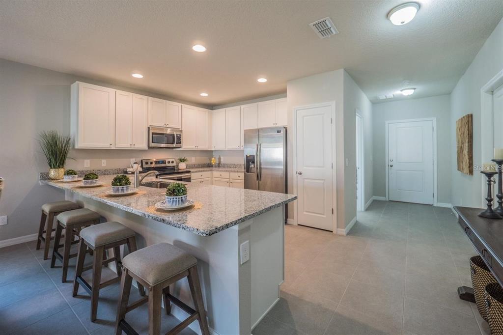 A kitchen with white cabinets, granite countertops, a breakfast bar, and stainless steel appliances — 248 CHESHIRE COURT, KISSIMMEE, FL