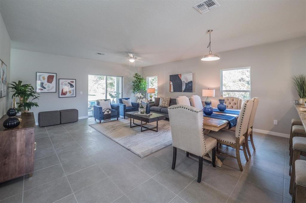 An open-concept living and dining area features tile flooring, neutral walls, and contemporary furniture — 248 CHESHIRE COURT, KISSIMMEE, FL