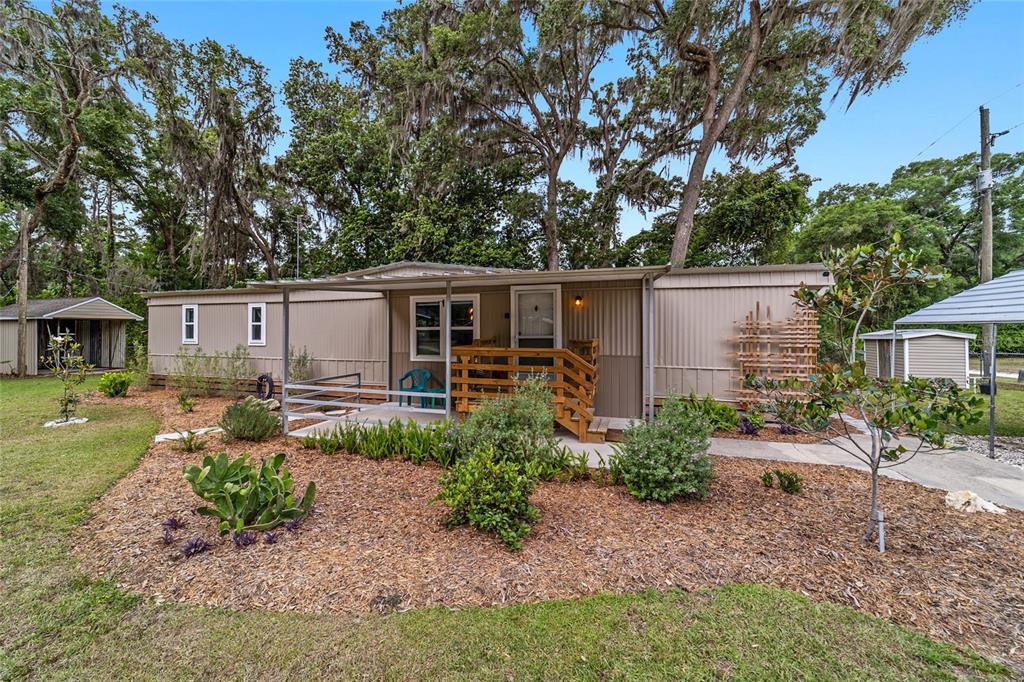 A single-story manufactured home with a wooden porch, metal siding, and landscaped front yard — 3460 SE 131ST PLACE, BELLEVIEW, FL