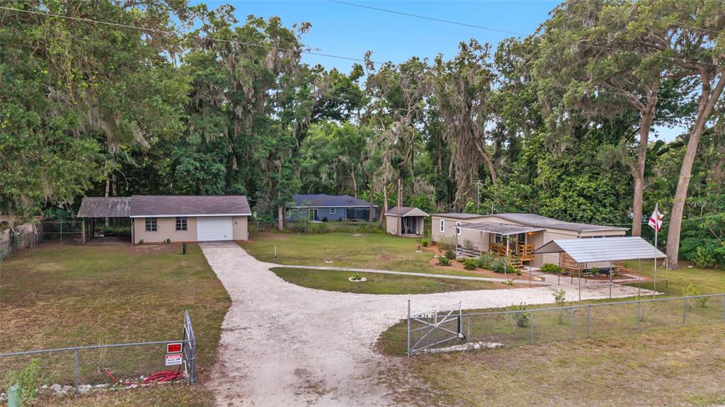 An aerial view shows two houses on a large, fenced lot with a gravel driveway — 3460 SE 131ST PLACE, BELLEVIEW, FL