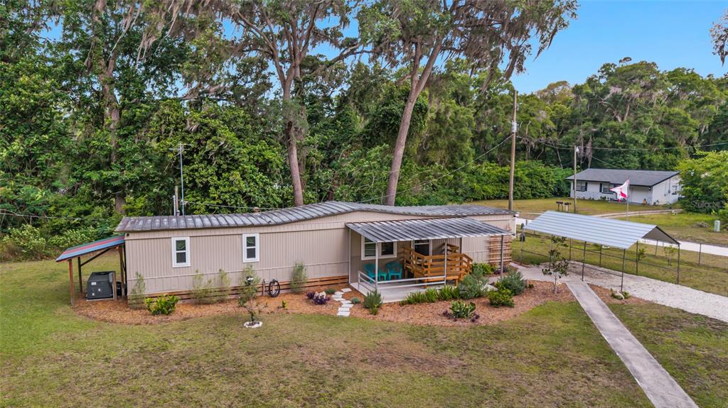 An exterior view of a tan mobile home with a metal roof and front porch — 3460 SE 131ST PLACE, BELLEVIEW, FL