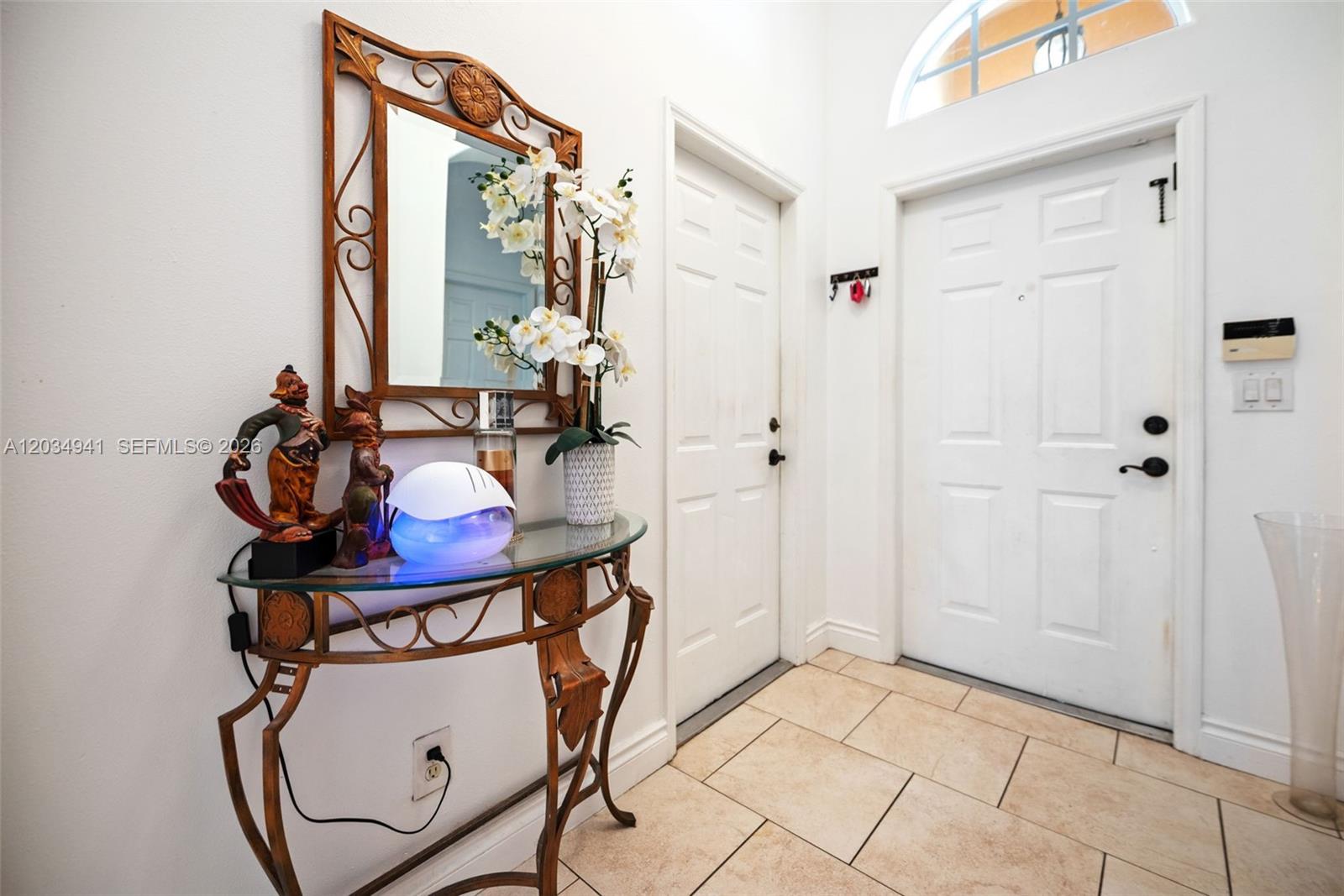 An entryway features a glass-topped console table, a decorative mirror, and white doors — 12870 SW 53rd St, Miramar FL 33027, MIRAMAR, FL