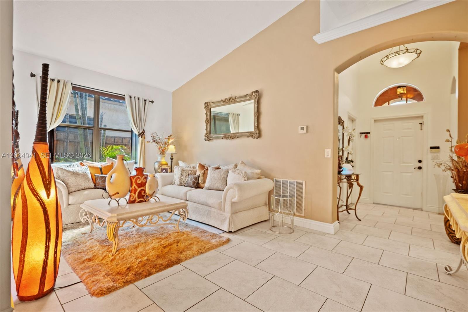A living room features a vaulted ceiling, tiled floors, a sofa, and a tall floor lamp — 12870 SW 53rd St, Miramar FL 33027, MIRAMAR, FL