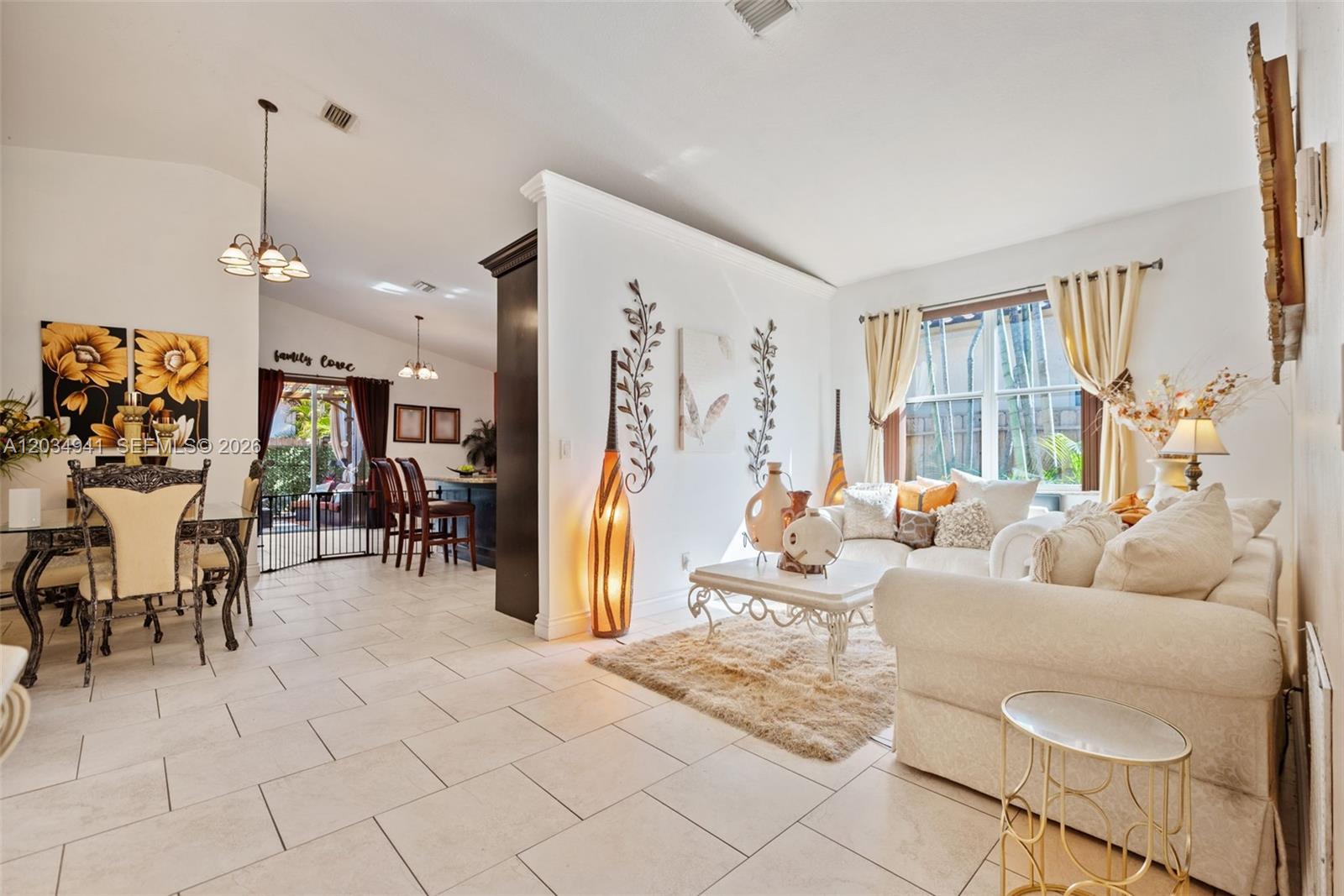 A bright living and dining area features white tile floors, neutral furniture, and decorative wall accents — 12870 SW 53rd St, Miramar FL 33027, MIRAMAR, FL