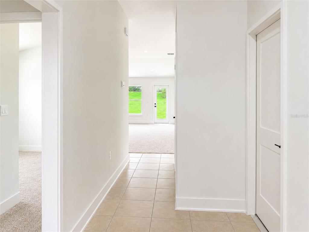 A tiled hallway leads to a carpeted living area with a glass door to the outdoors — 247 VERNY GROVE LANE, LEESBURG, FL
